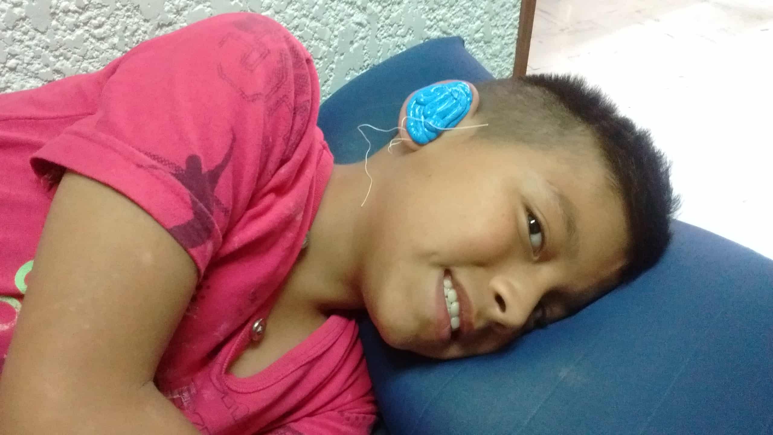 Niño sonriendo con su nuevo aparato auditivo azul