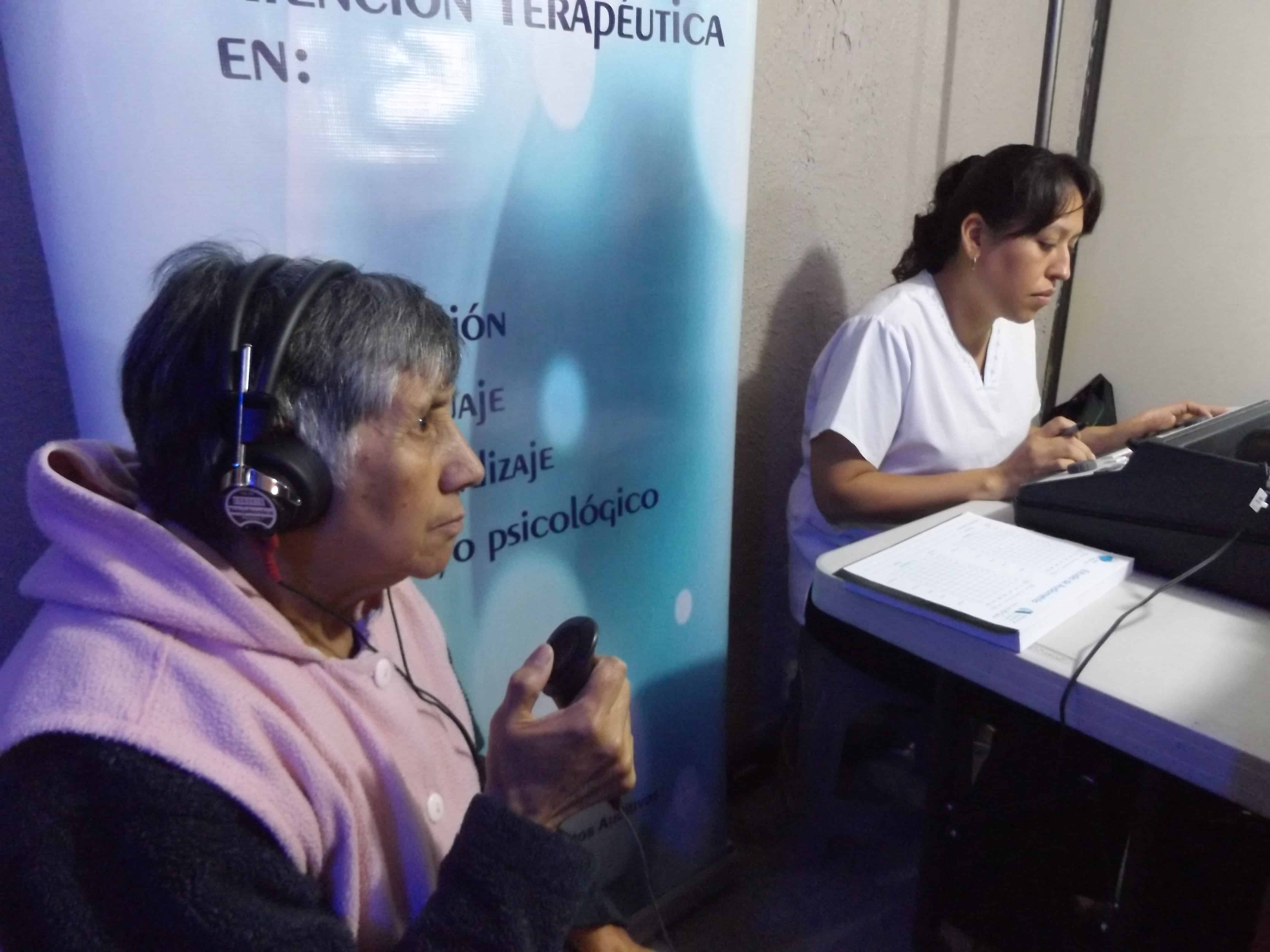 Niño usando un aparato auditivo azul, sonriendo recostado