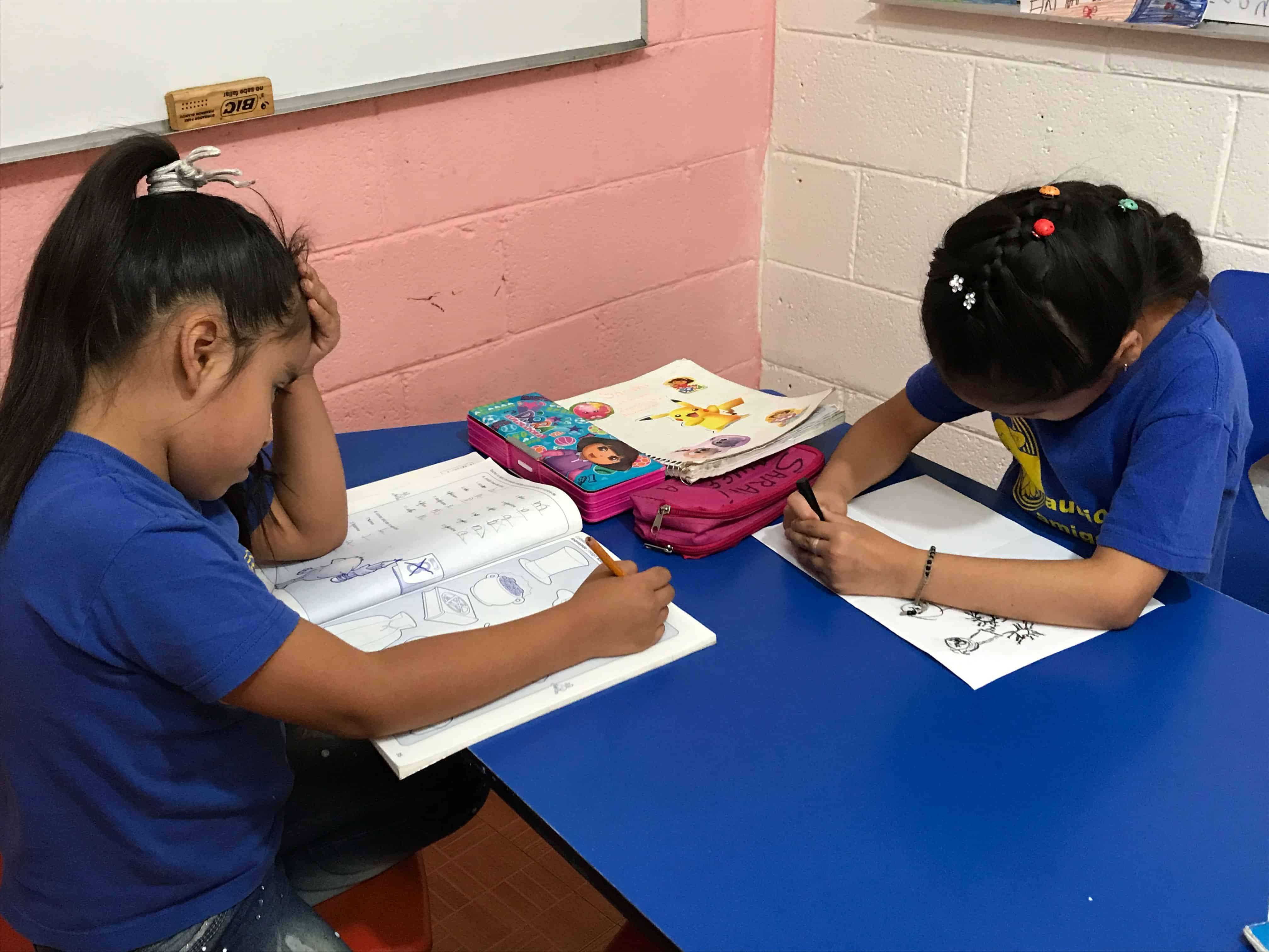 Niñas escribiendo en cuadernos durante una sesión de terapia de lenguaje